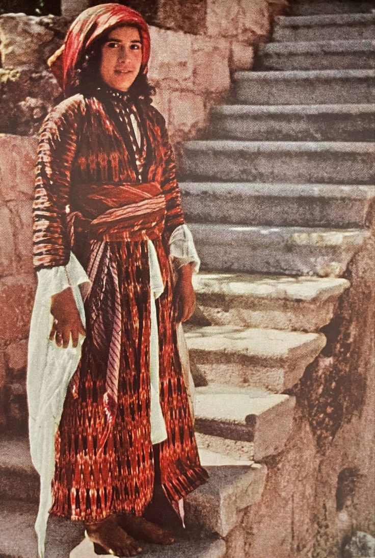 A young Palestinian girl stands on some stairs in Nazareth, Palestine wearing a Traditional Palestinain Thob. Sew to Speak
